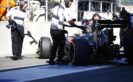 Team members push Fernando Alonso into the garage in the pit lane.