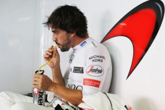 Fernando Alonso toma un trago en el garaje de boxes.